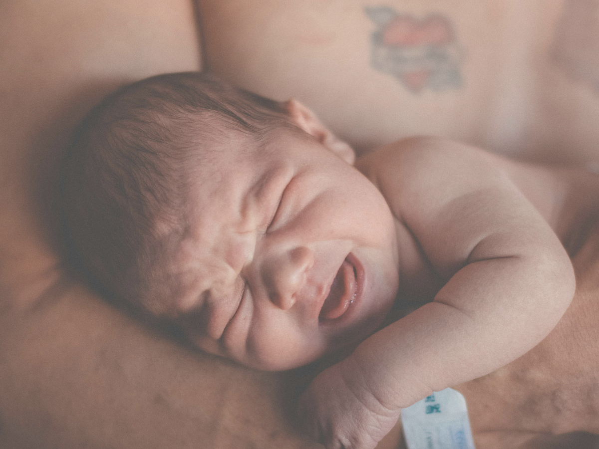Papa hält schreiendes Baby im Arm, symbolisiert Nähe und Unterstützung bei Regulationsstörungen.