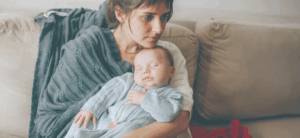 Ein ruhiges Baby liegt entspannt im Arm seiner Mutter, die es liebevoll hält. Das Bild symbolisiert die besondere Nähe und Fürsorge, die hochsensible Babys benötigen, um sich sicher und geborgen zu fühlen.